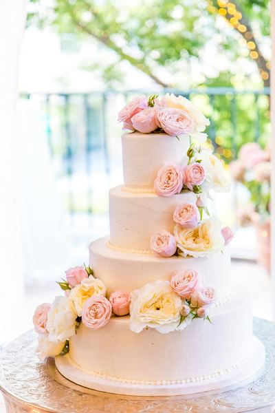 Tiered white wedding cake decorated with fresh flowers